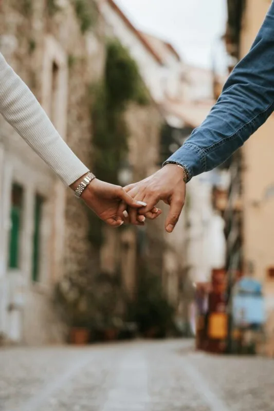 A couple holding hands in a picturesque Italian street, showing love and connection.